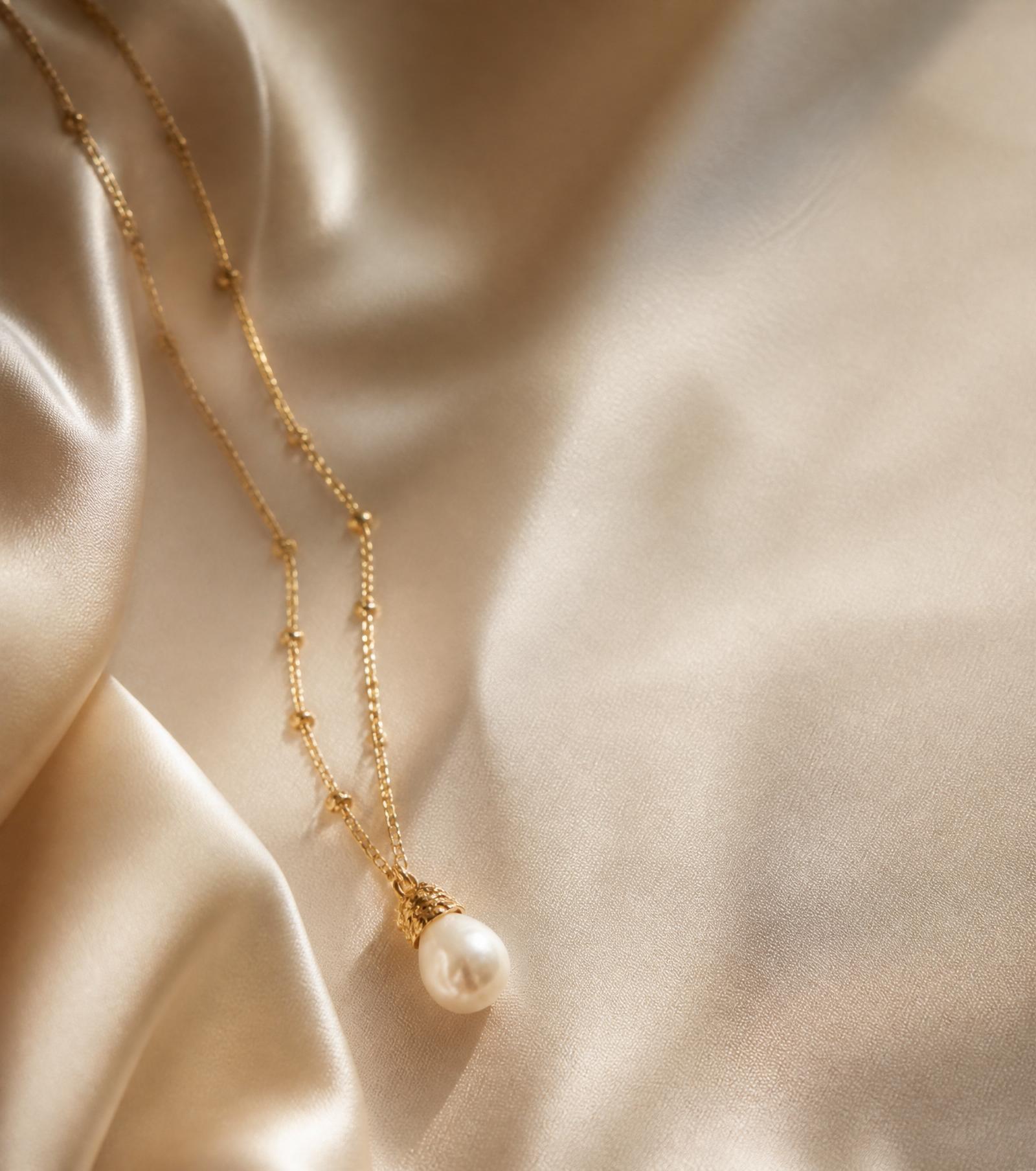 Handmade gold and pearl necklace on ivory silk